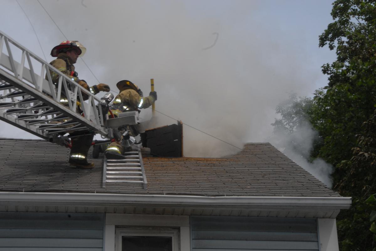 Fire Crew on a Ladder Looking down Into a Mock Structure Fire